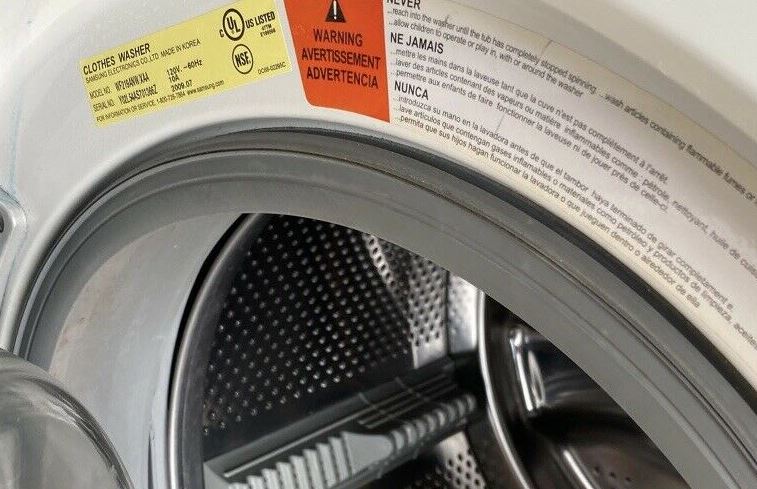 Adhesivo informativo bajo la escotilla de la lavadora